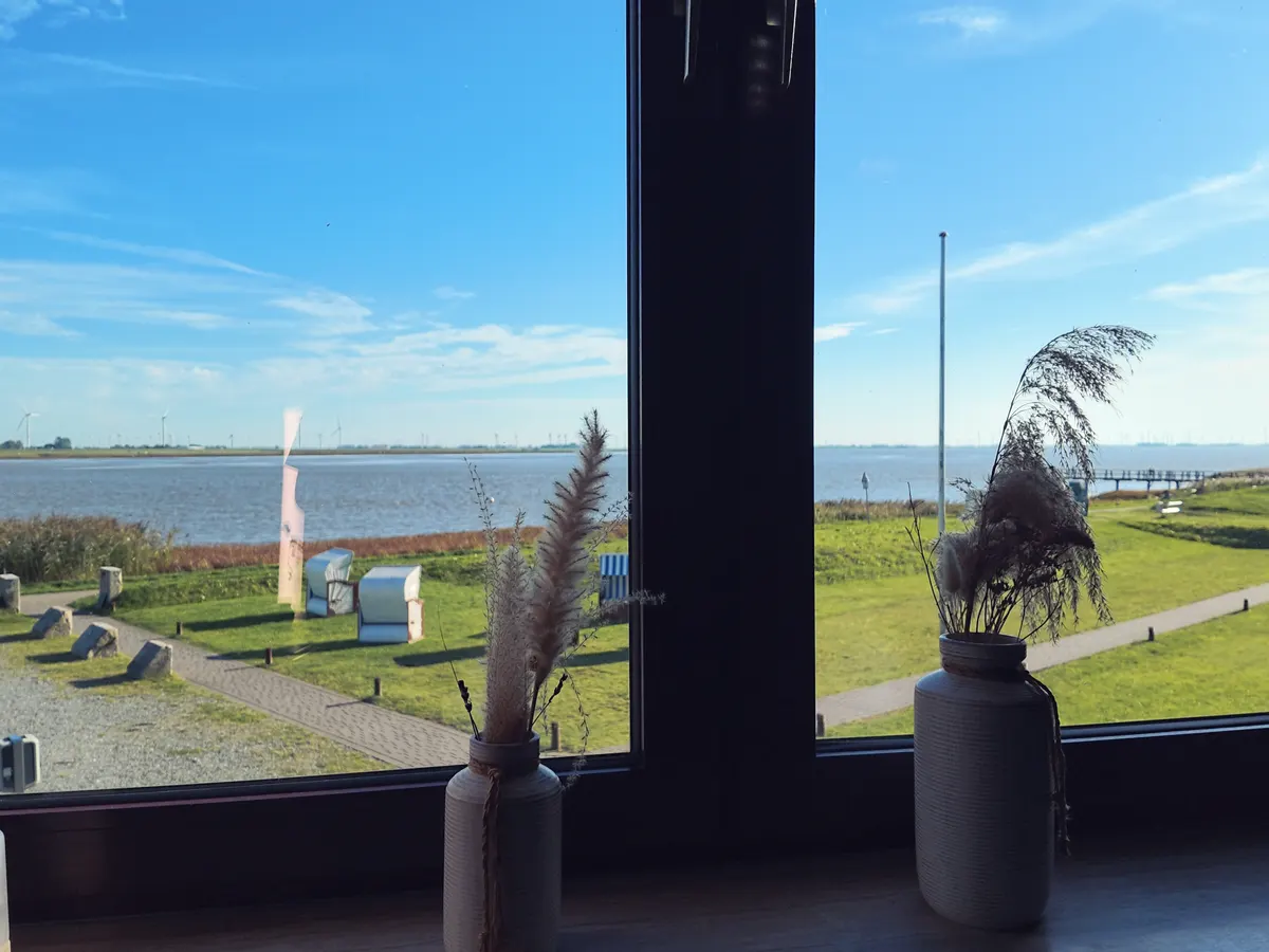 Blick aus dem Fenster des Restaurants tween auf die Eider und die Strandkörbe am Deich in Tönning